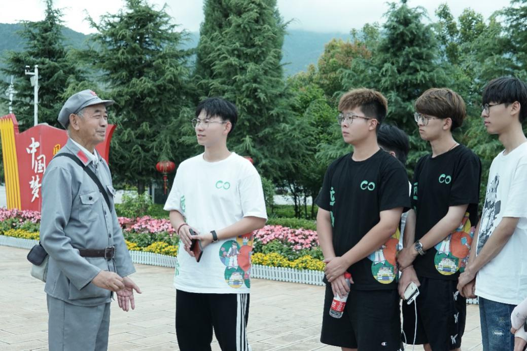 实践队成员在鹤庆纪念碑广场聆听老党员讲述红军长征故事